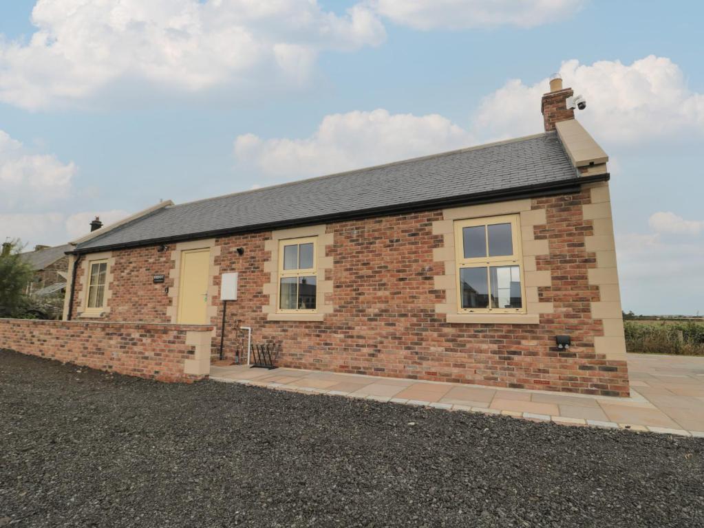 een stenen huis met een stenen muur bij Whinny Cottage in Alnwick