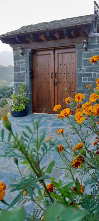 a building with a wooden door and a bunch of flowers at Point of view 1 in Pramanta
