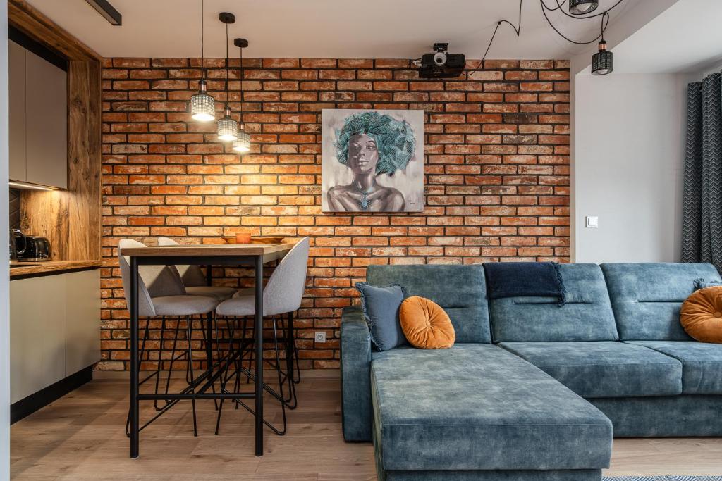 uma sala de estar com um sofá azul e uma parede de tijolos em RentPlanet - Lokum Vena em Breslávia