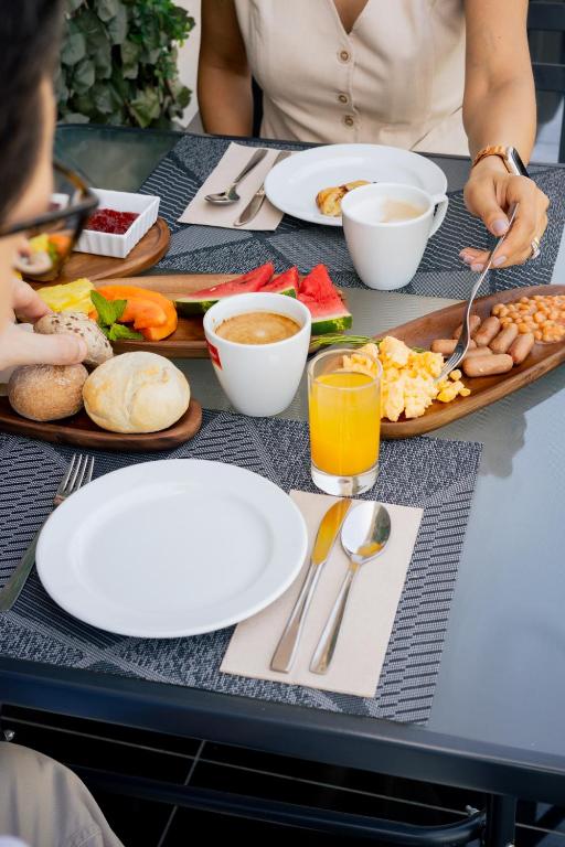 A laid breakfast table with coffee, juice, fruit, bread, cheese and eggs.