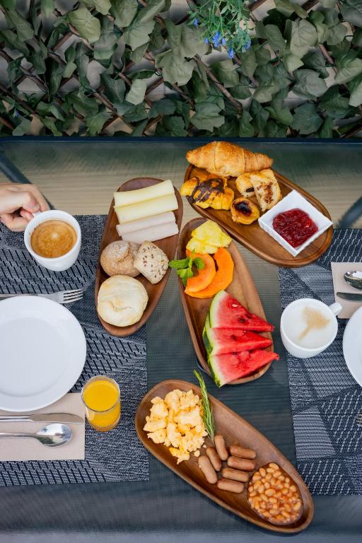 A set breakfast table featuring pastries, fruit, eggs, sausages, beans and coffee.