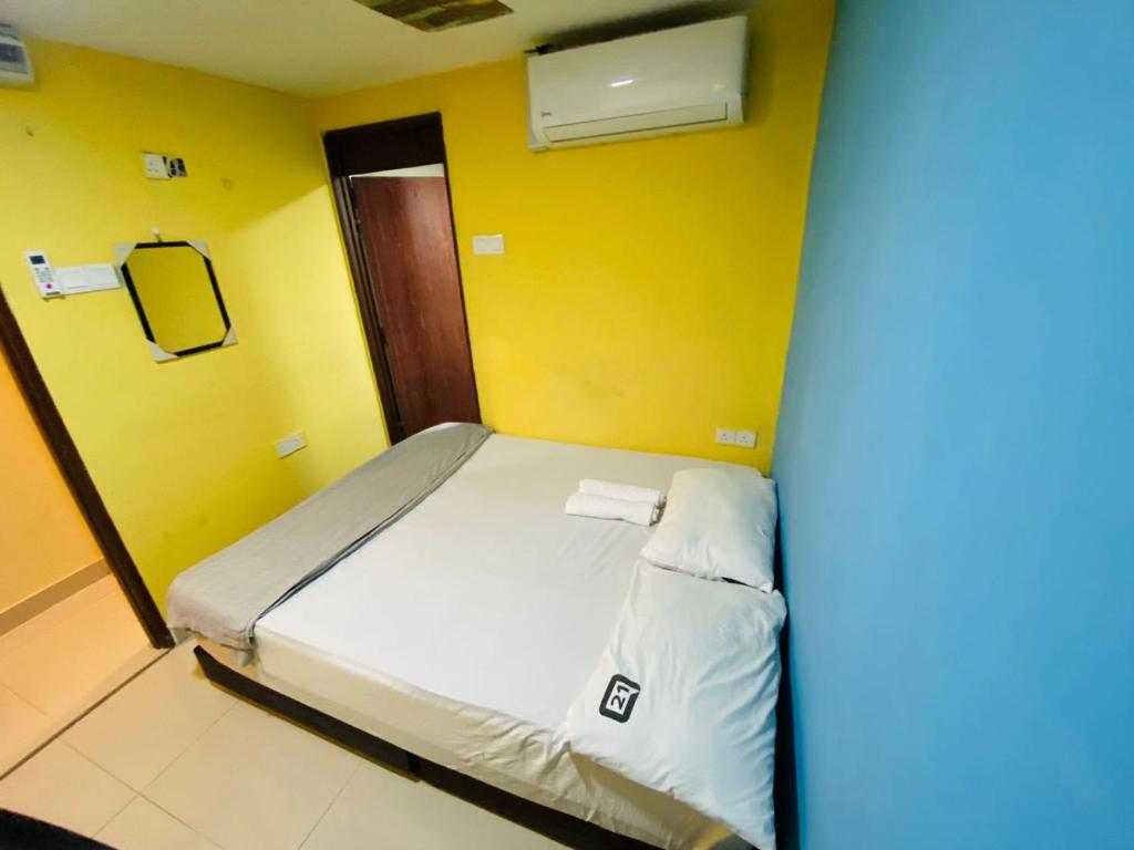 a bed in a room with a yellow wall at RAS International Hotel in Kuala Lumpur