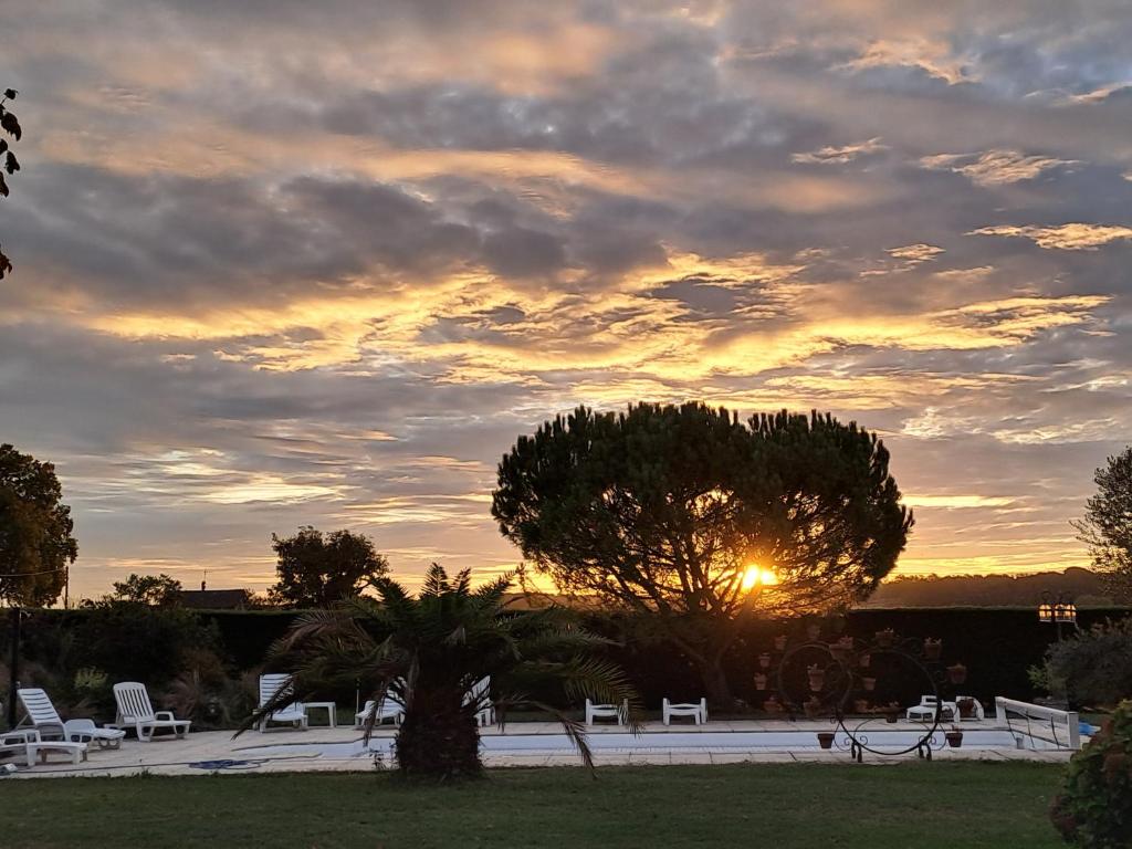 un coucher de soleil avec un groupe de chaises et un arbre dans l'établissement La Garenne, à Virazeil