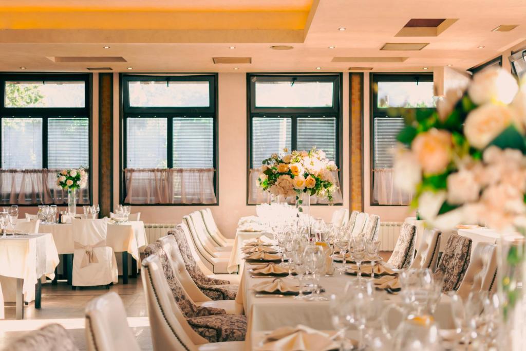 een eetkamer met witte tafels, stoelen en bloemen bij Complex Praveshki Hanove in Pravets