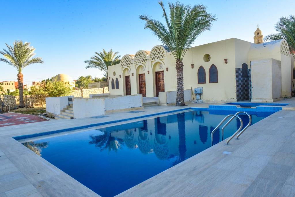 - une piscine en face d'une maison avec des palmiers dans l'établissement قرية تونس السياحية, à Tunis