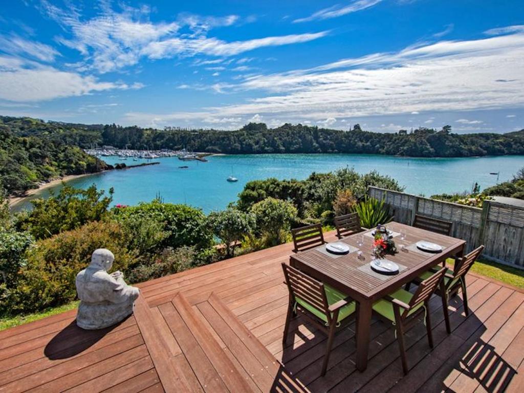 a wooden deck with a table and chairs with a view of a river at Sea Blue Heaven in Tutukaka