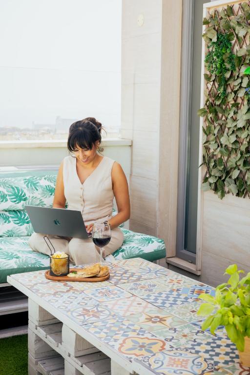 A small outdoor work-and-dining setup with a laptop, cushioned bench and city outlook.