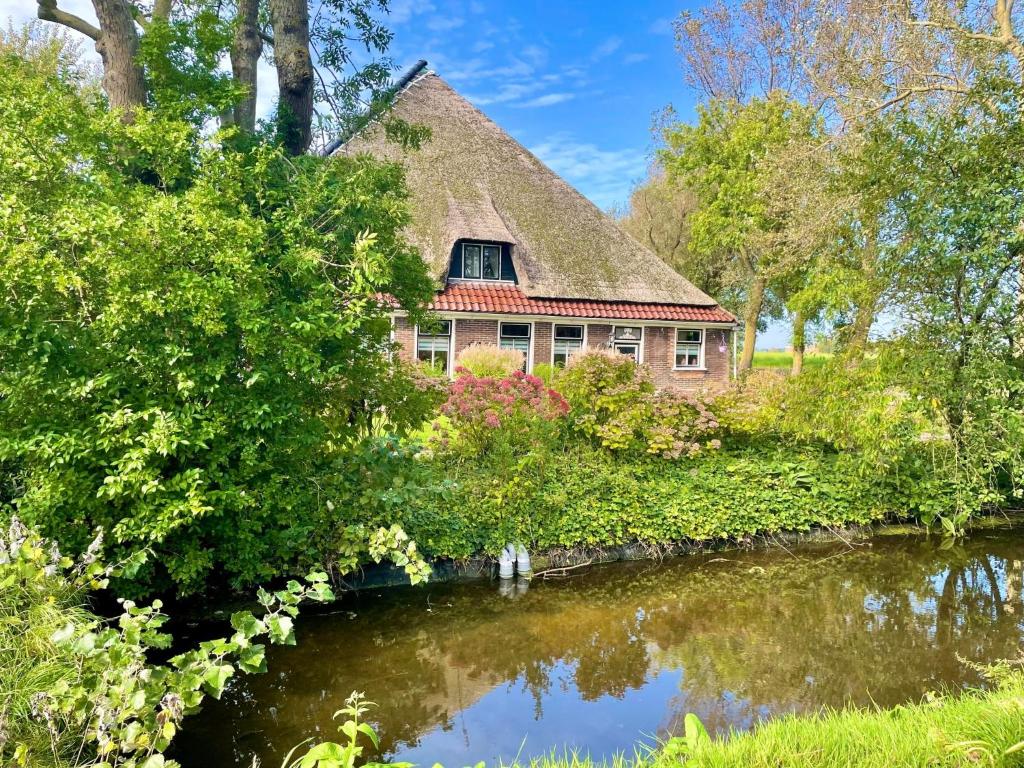 uma casa com telhado de palha ao lado de um rio em Holiday Home De Dars by Interhome em Stolpen
