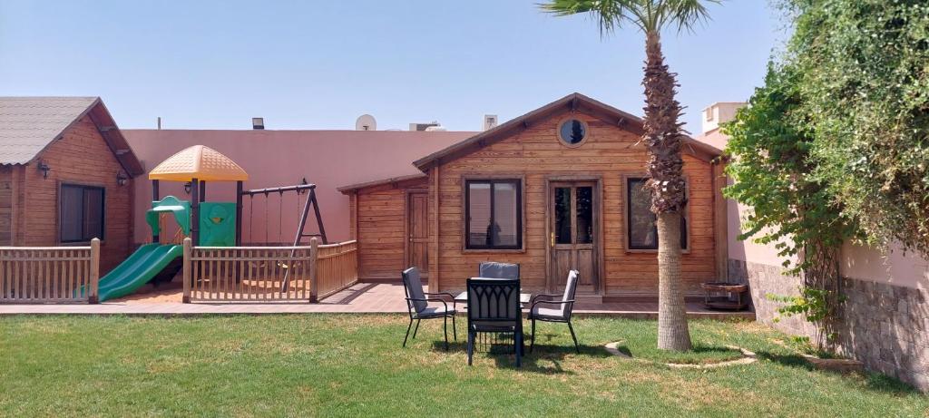 a house with a table and chairs and a playground at Tola Holiday House Al Rimal in Riyadh