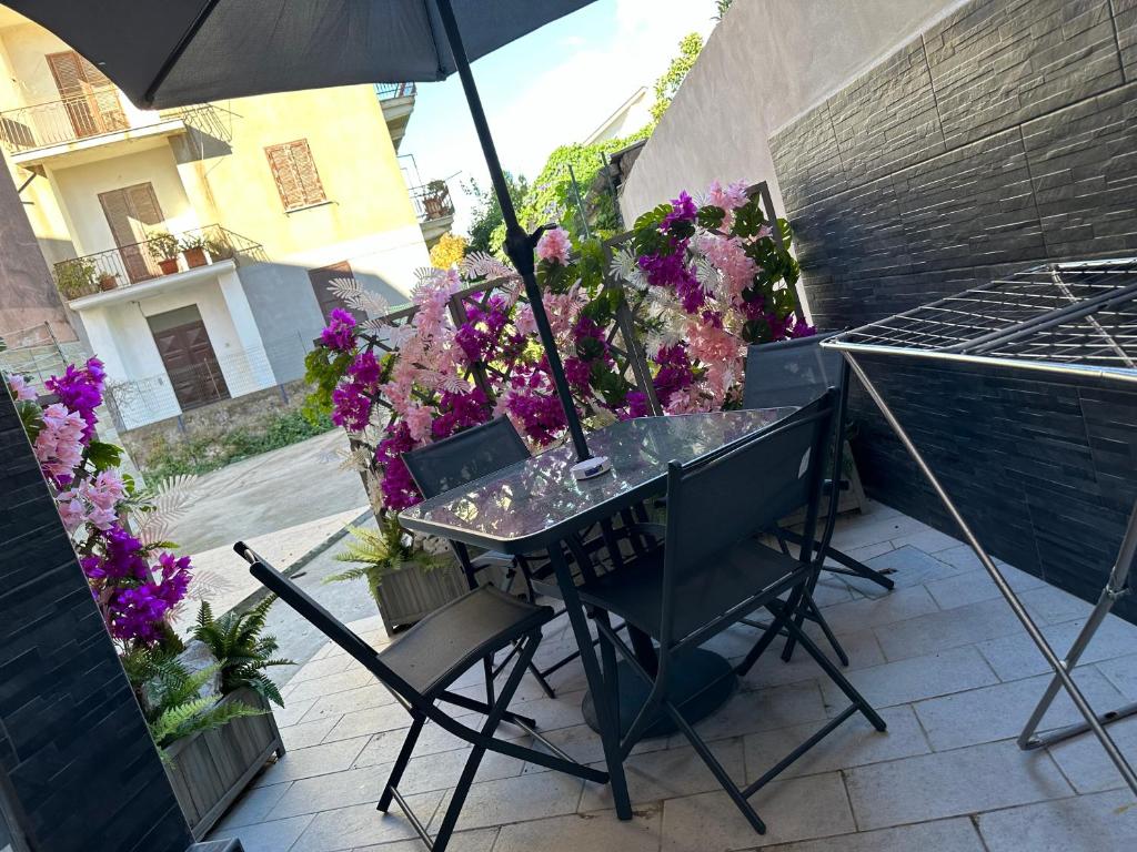 una mesa con sombrilla en un patio con flores en Rossella Silver House, en Minturno