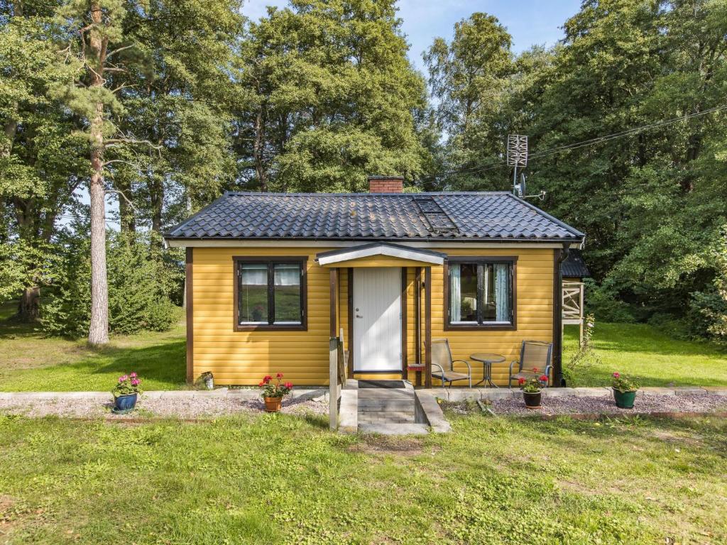 a small yellow tiny house in a field at Holiday Home Kjuge Gula Huset by Interhome in Fjälkinge