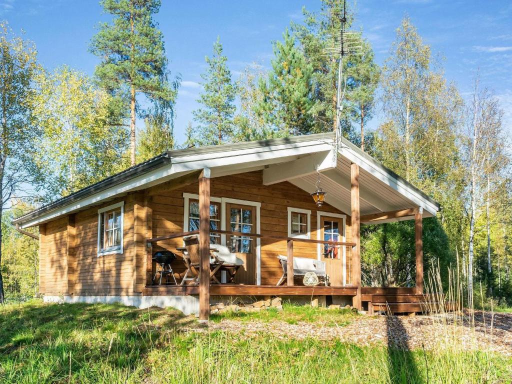a log cabin in the woods with a wrap around porch at Holiday Home Niemenkärki by Interhome in Kortteinen