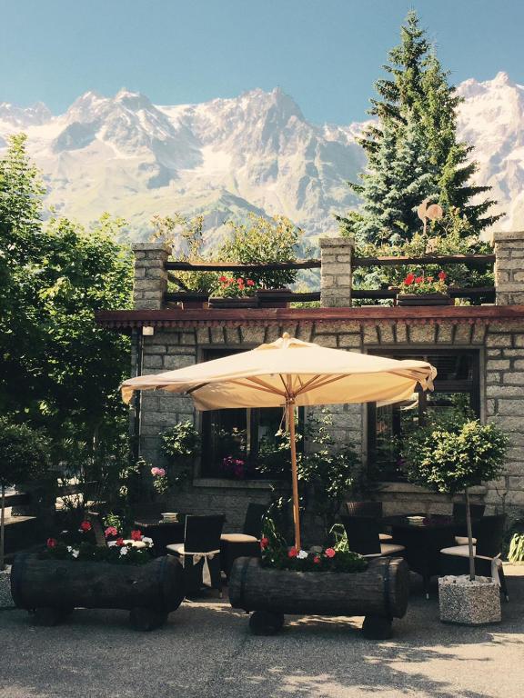 an umbrella and tables and chairs with a mountain in the background at Hotel Dei Camosci in Courmayeur