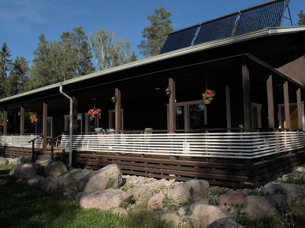 um grande edifício com um alpendre e algumas rochas em Holiday Home Lammassaari by Interhome em Kuusjärvi