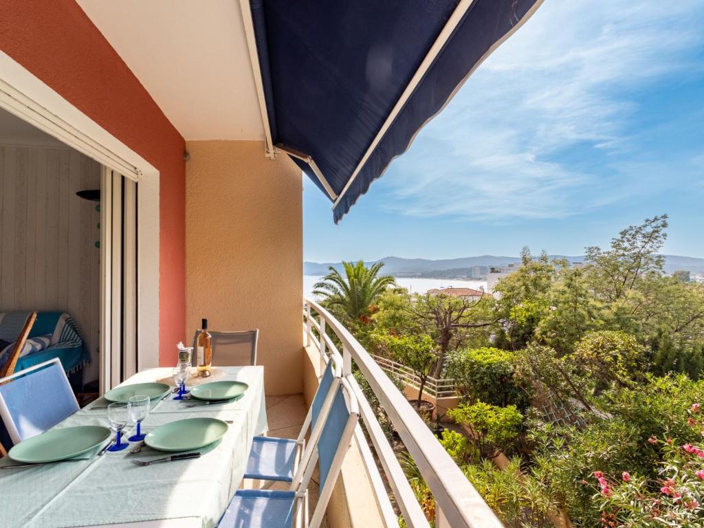 een balkon met een tafel en stoelen en uitzicht op de oceaan bij Apartment Le Marbello by Interhome in Le Lavandou
