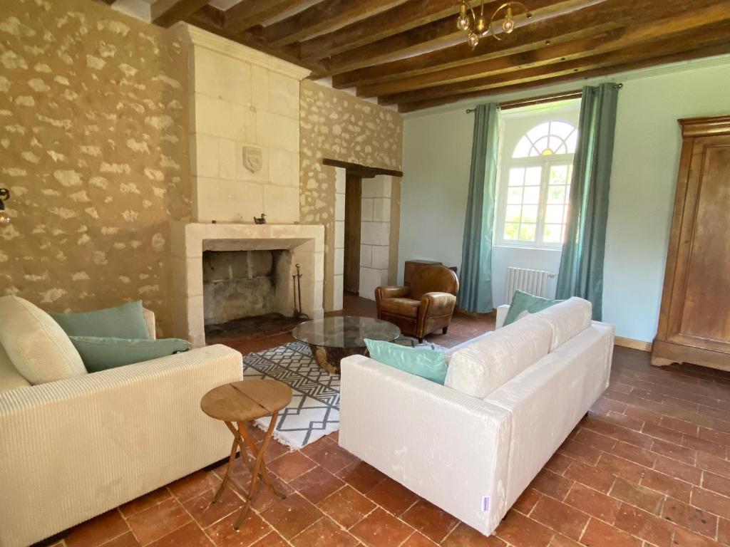 a living room with white couches and a fireplace at Maison de Campagne avec Piscine, Vallée de la Loire in Sarcé