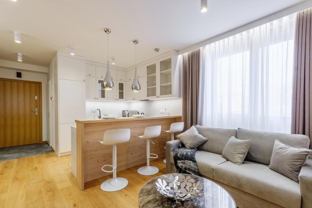 a living room with a couch and a kitchen at FLORENCJA - nowy apartament w centrum miasta z zadaszonym parkingiem w cenie in Nowy Targ