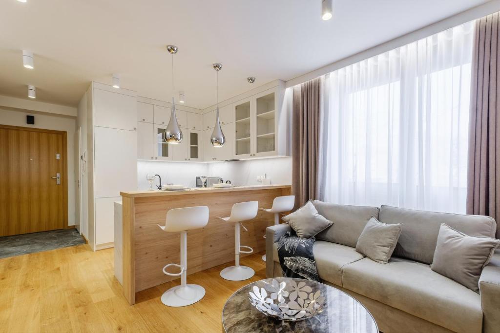 a living room with a couch and a kitchen at FLORENCJA - nowy apartament w centrum miasta z KLIMATYZACJĄ oraz zadaszonym parkingiem w cenie in Nowy Targ
