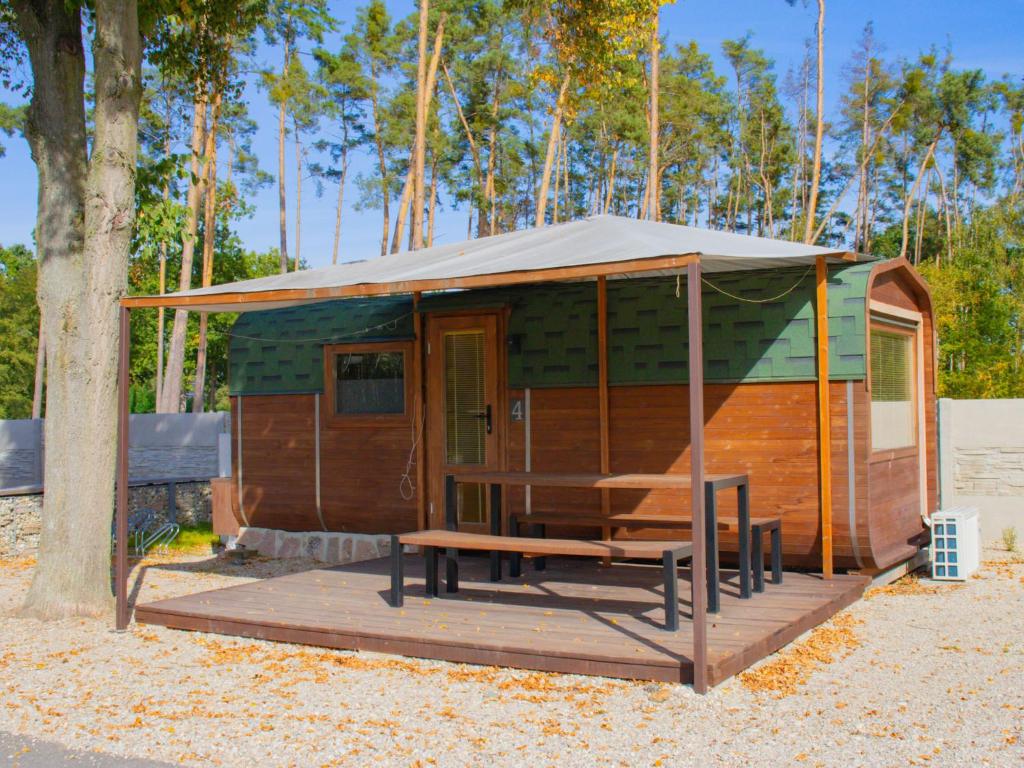 eine Holzhütte mit einer Bank und einem Zelt in der Unterkunft Holiday Home Kemp Stříbrný rybník-4 by Interhome in Hradec Králové