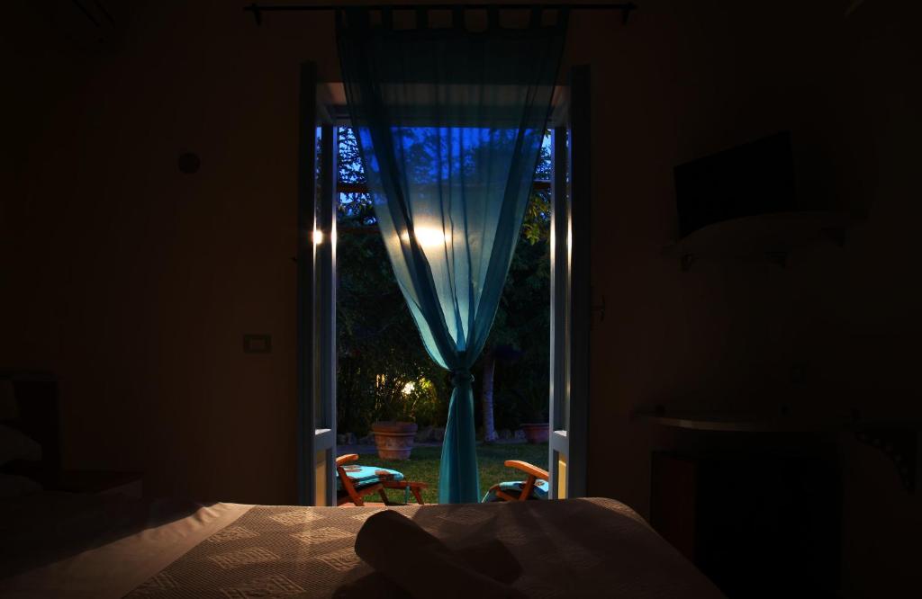 a bedroom with a window with a blue curtain at Solcalante in Procida