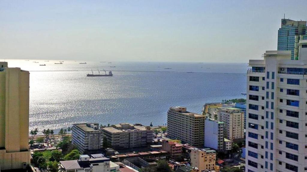 a view of the ocean from a city with buildings at Discover Unmatched Luxury: 75% Off Deluxe Ocean-View Room in Central Manila, Free Pool & Sauna, Prime Location near US Embassy, NAIA, Makati, BGC, Mall of Asia, Chinatown. Immerse in Elegance with Balcony. Limited-Time Offer - Book Now in Manila