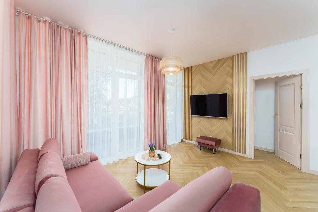 a living room with a pink couch and a tv at Apartament Pudrowy Ku Morzu by HolidaySun in Sianozety