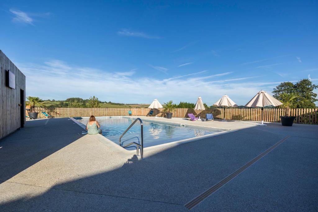 a woman is sitting next to a swimming pool at DOMAINE SAÂNE ET MER in Quiberville