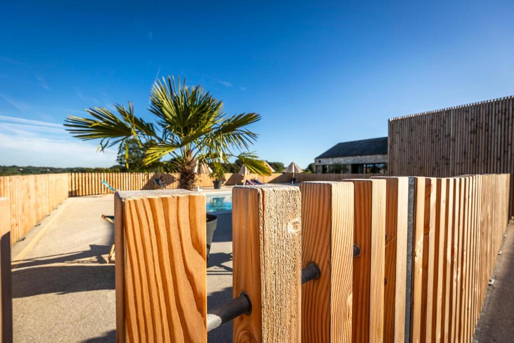 a wooden fence with a palm tree in the background at DOMAINE SAÂNE ET MER in Quiberville