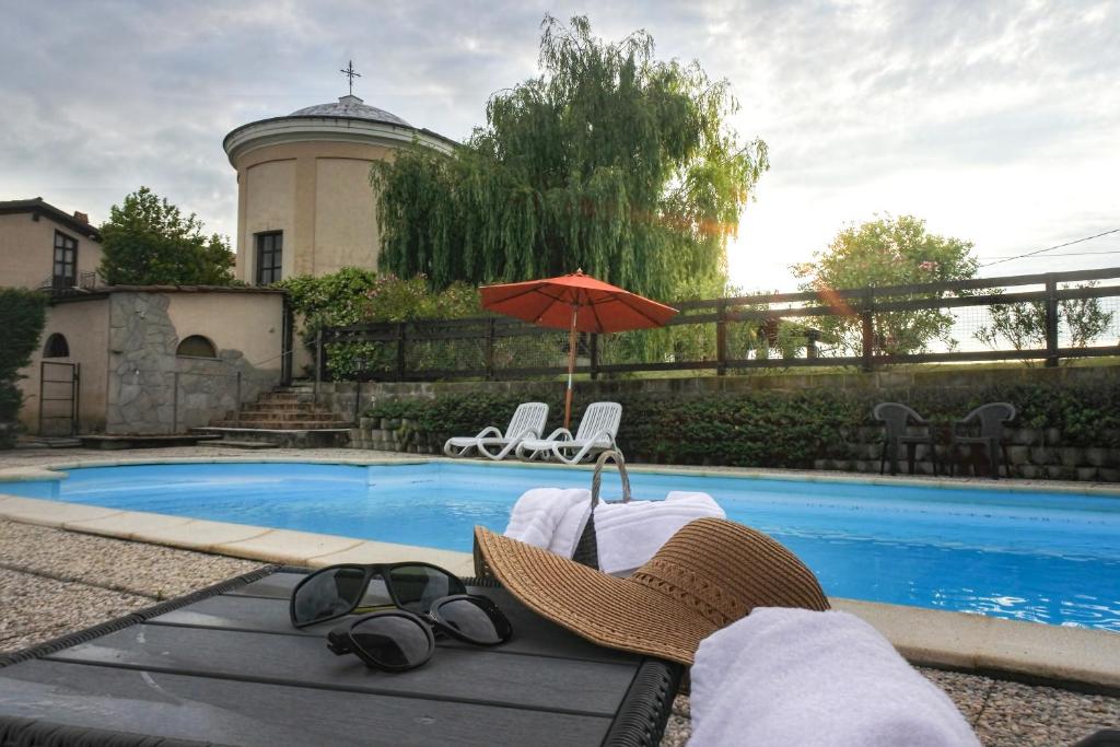 um par de chapéus e um par de óculos de sol e um guarda-chuva ao lado de uma piscina em Azienda Agricola Tenuta del Barone em Calliano