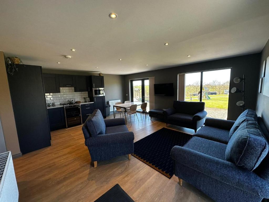 sala de estar con 2 sofás azules y cocina en Countryside Chalet near Glasgow en Glasgow