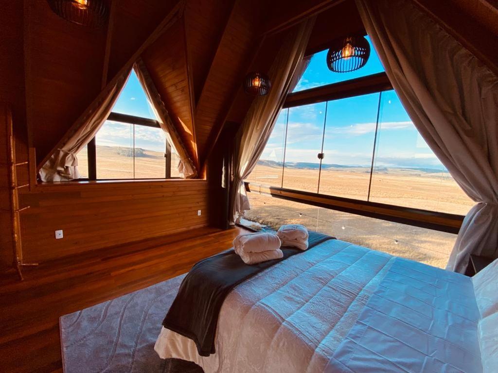 a bedroom with a bed with a view of the desert at Cabanas Arroio Da Serra in Cambara do Sul