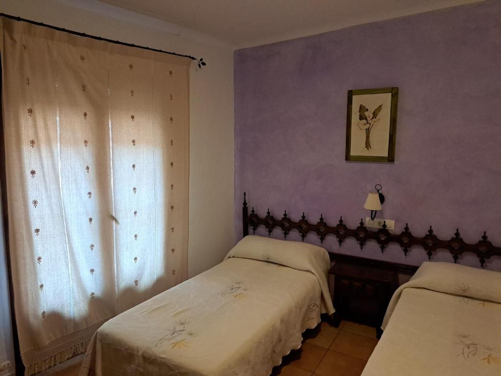 GodojosにあるCASA RURAL LA SOLANAの紫色の壁の部屋にベッドが2つある