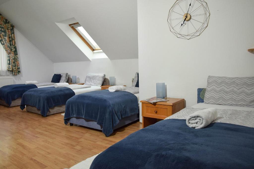 a bedroom with three beds and a clock on the wall at Kiskut Liget Pension in Győr