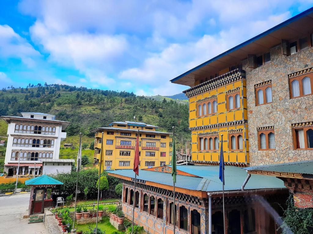 a group of yellow buildings with a mountain in the background at Hotel Migmar in Thimphu