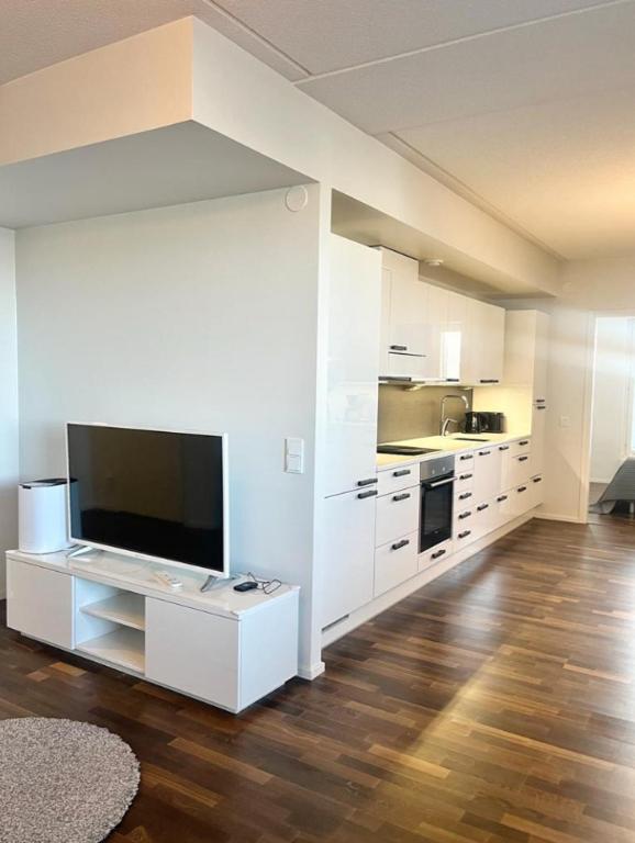 a kitchen with white cabinets and a flat screen tv at Kotimaailma - Premium 2 bedroom apartment with Terrace & Sauna in Vantaa
