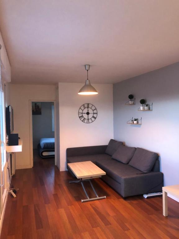 a living room with a couch and a clock on the wall at Appartement T2 - Proche RER in Sartrouville