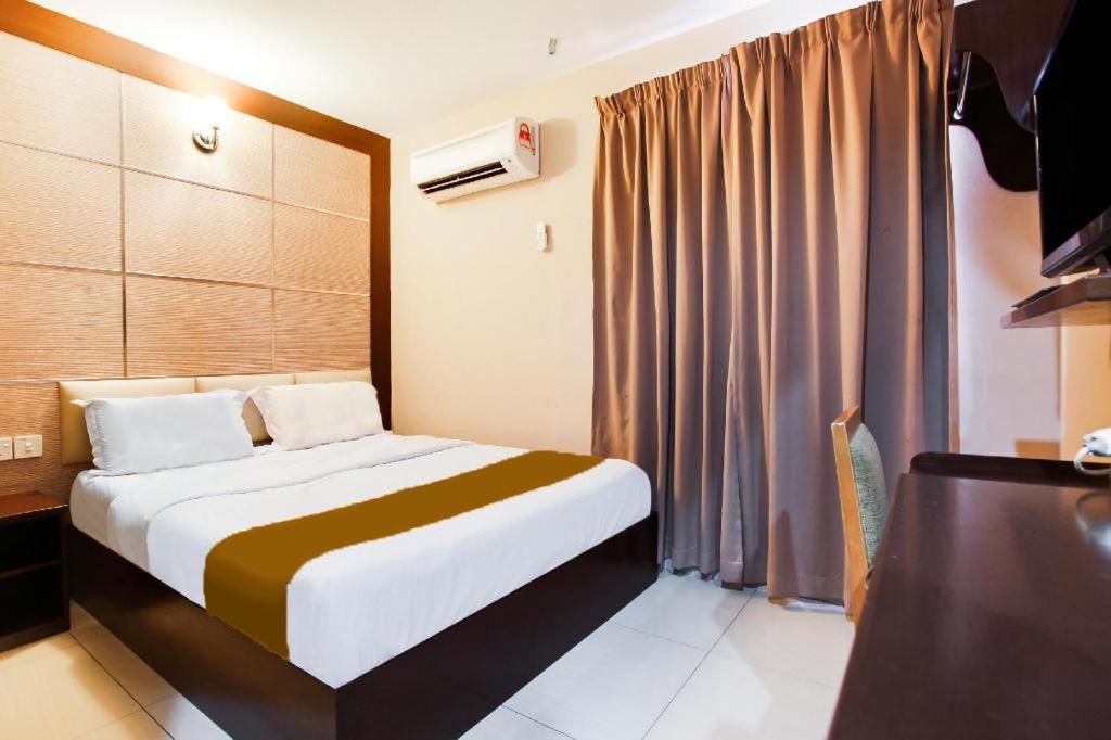um quarto de hotel com uma cama e uma televisão em Sejati Hotel em Sitiawan