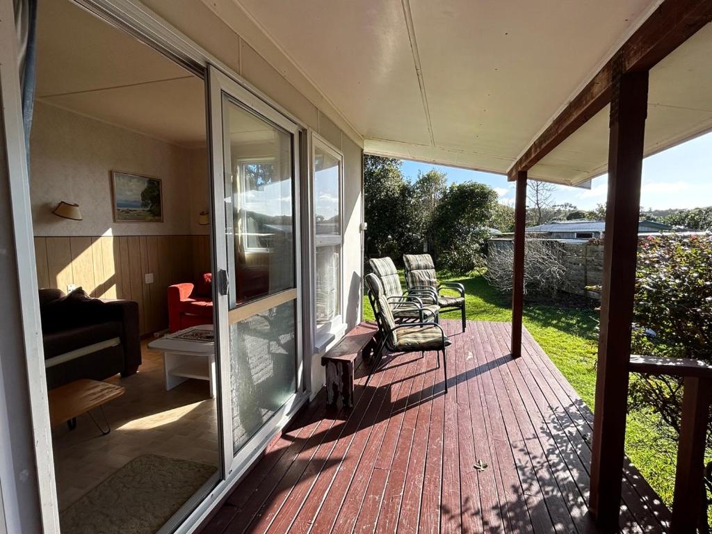 a screened in porch with two chairs and a couch at Kiwi Classic in Matapouri