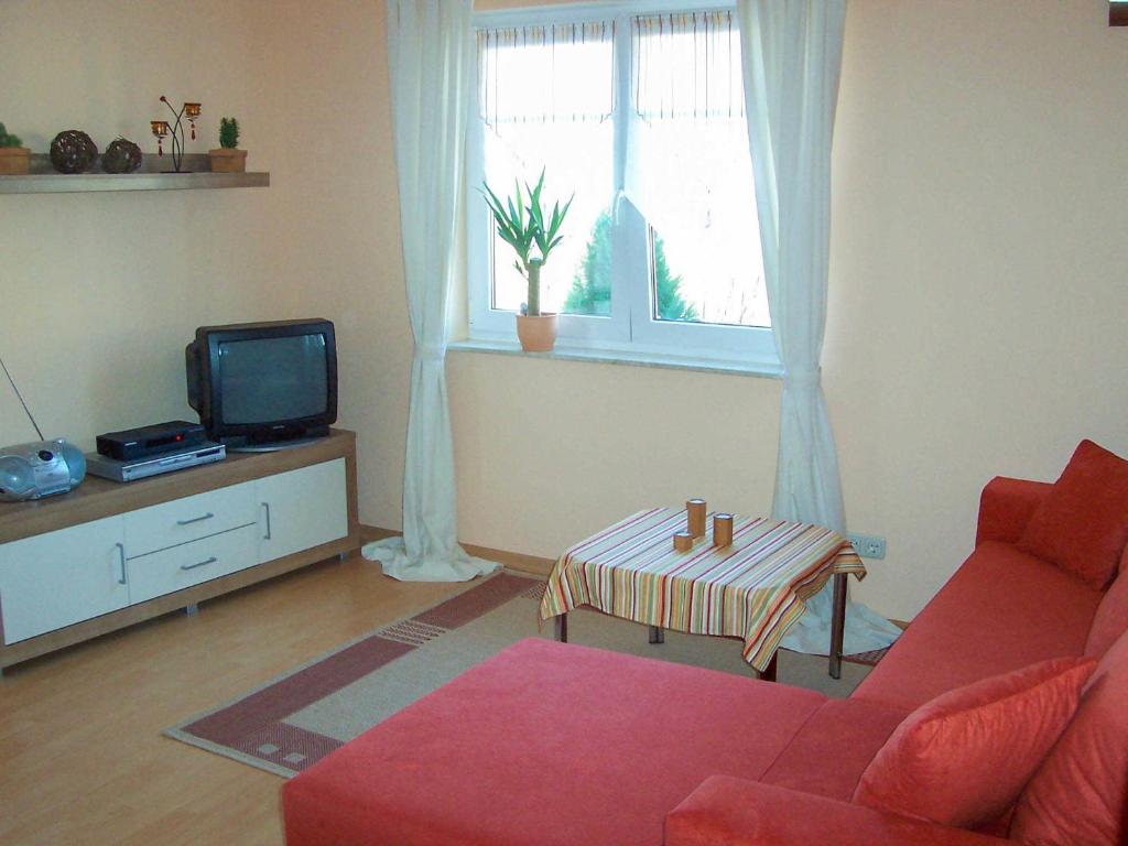 ein Wohnzimmer mit einem roten Sofa und einem TV in der Unterkunft Ferienwohnung im Ostseeblick in Wismar