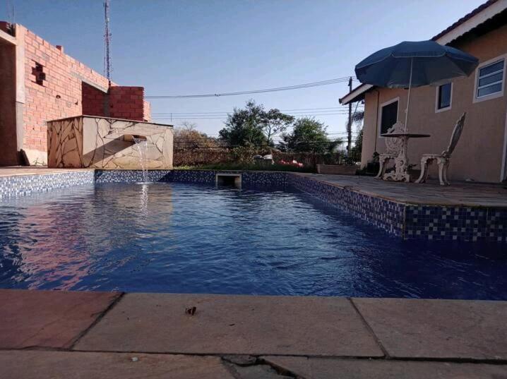 einen Pool mit Sonnenschirm neben einem Haus in der Unterkunft Hospedagem Em Santana de Parnaíba in Santana de Parnaíba