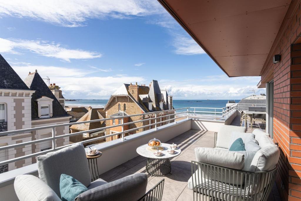 Un balcón con sillas y una mesa y el océano. en Cap de Jade - Jolie vue sur plage de Rochebonne, en Saint-Malo