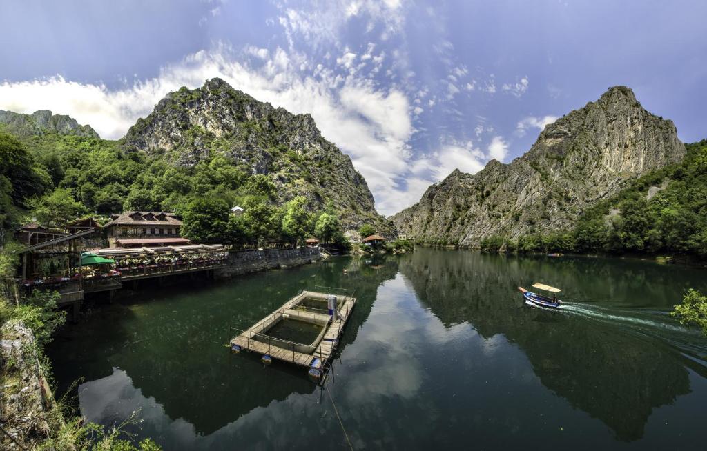 a boat on a river with mountains in the background at Canyon Matka Hotel in Matka