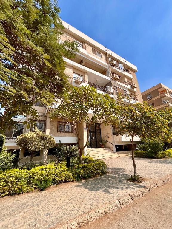 un gran edificio de apartamentos con un árbol delante en Cozy holiday apartment in Maadi, en El Cairo