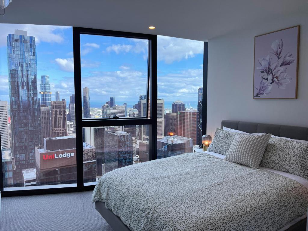 Hotel Melbourne CBD 2B2B1S with City & Sea Views, a bedroom with a large window with a view of a city at Melbourne CBD 2B2B1S with City & Sea Views in Melbourne