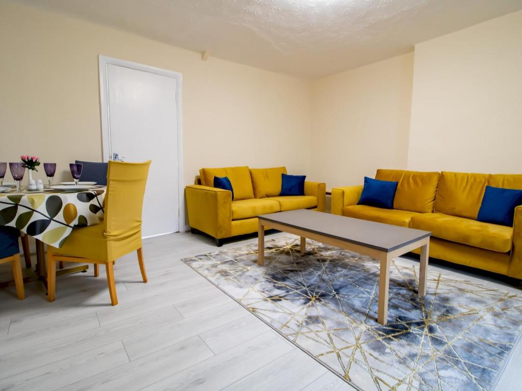 a living room with yellow couches and a table at Pass the Keys Spacious Well Equipped Flat in Gosforth