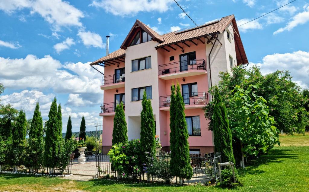 a pink building with trees in front of it at Pensiunea Emma in Sâmbăta de Sus