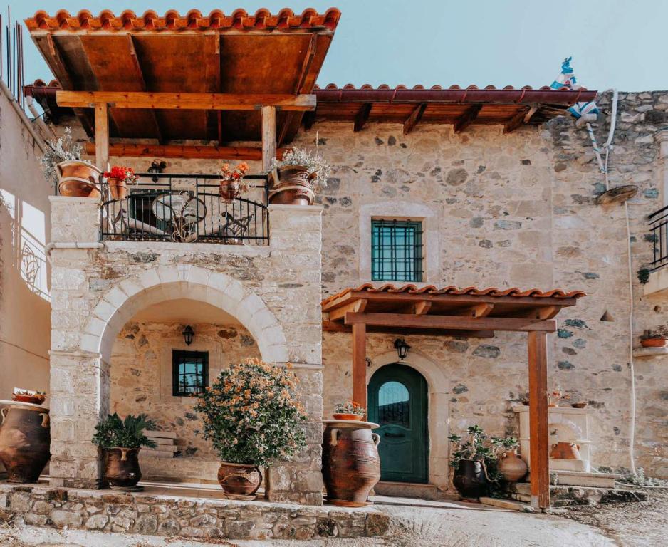 a stone building with a balcony and a green door at Traditional stone house Ariadne near Matala beach in Petrokefálion
