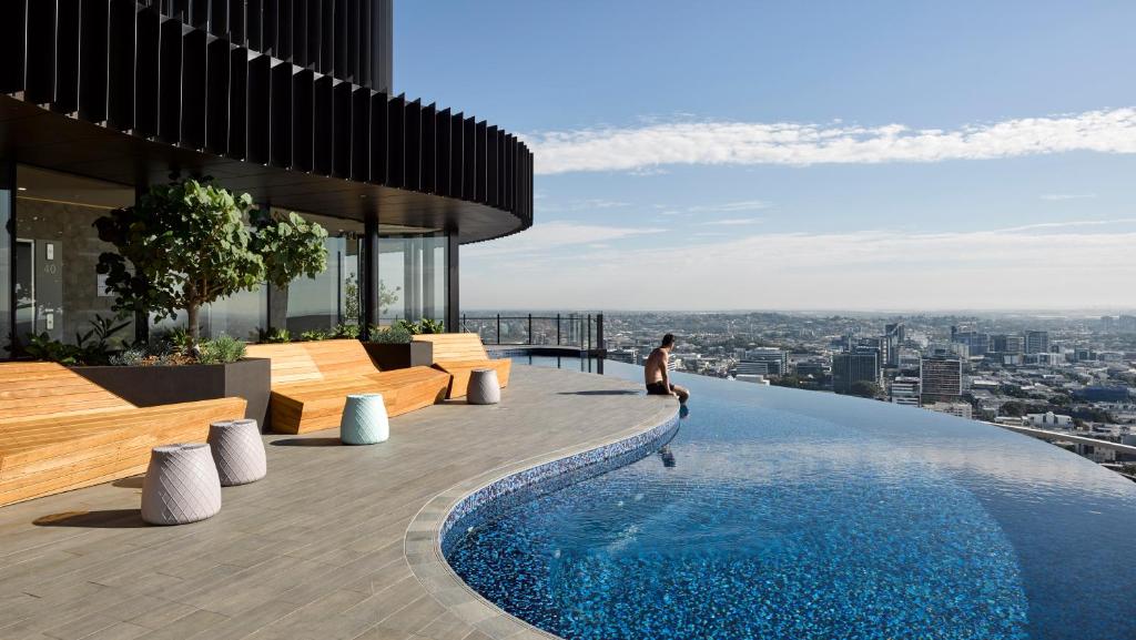 a man sitting on the edge of a building with a swimming pool at Spire Residences by the Spire Manager in Brisbane