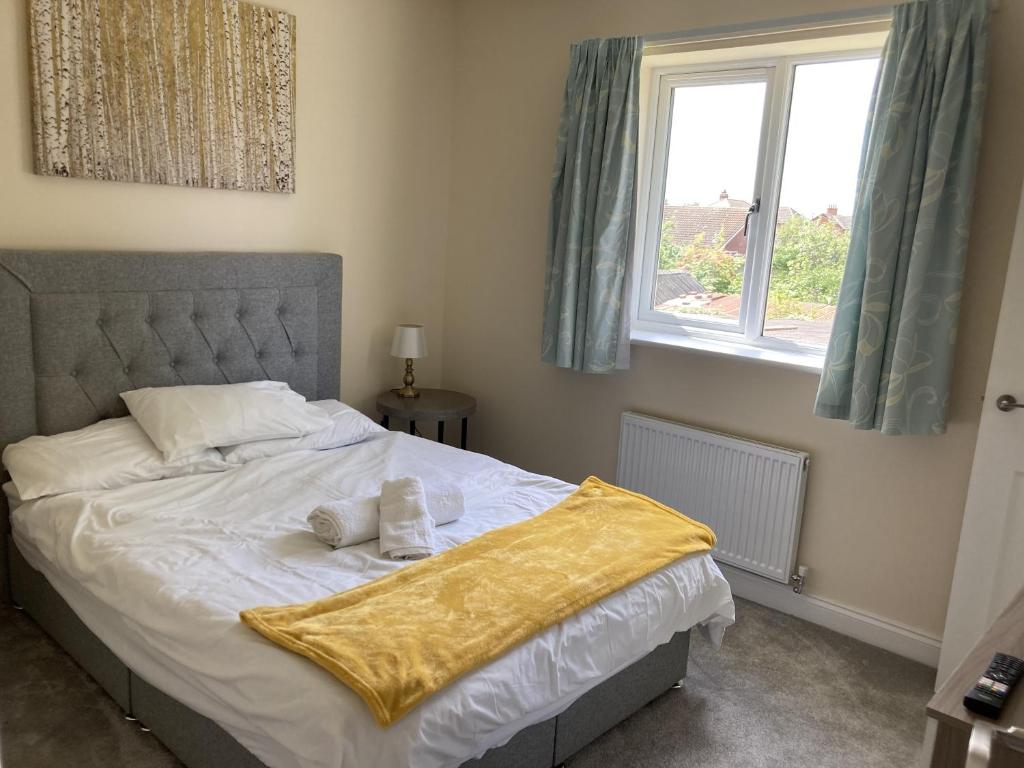 a bedroom with a bed with a yellow blanket on it at Newly built 3 Bed house with ample parking 1 in Balderton