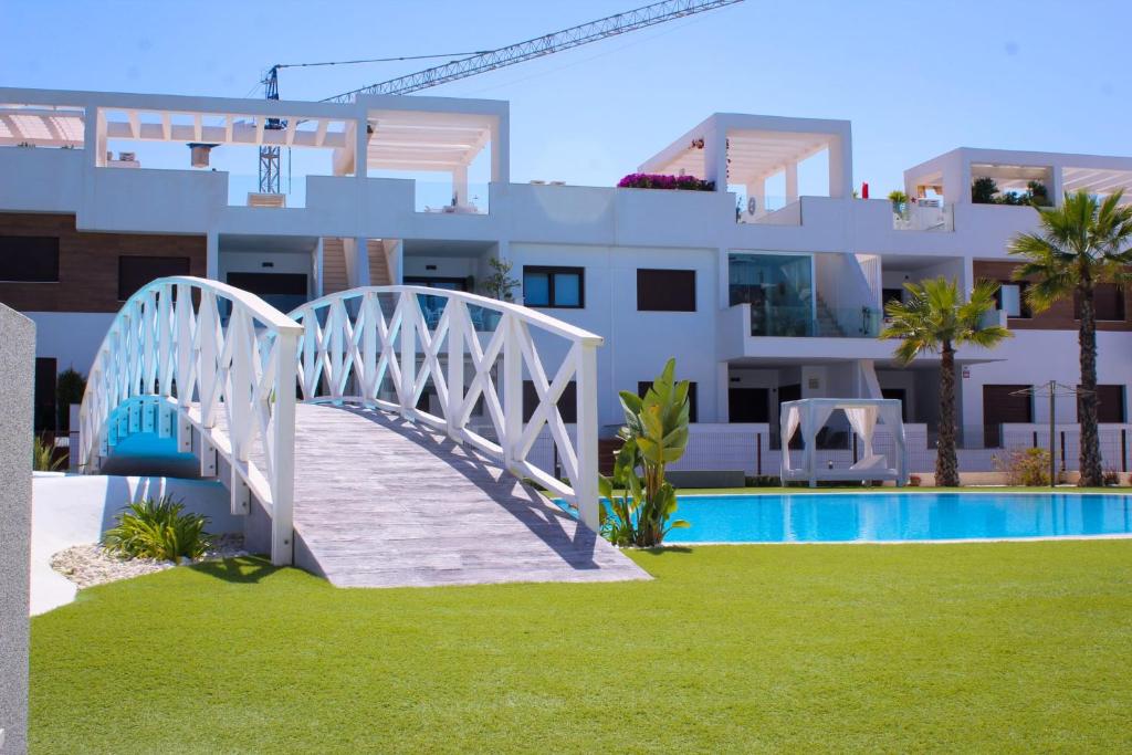 a bridge over a pool in front of a building at Beautiful Condo in Laguna Beach Resort overlooking Laguna Rosa In Torrevieja With 2 Bedrooms and 2 Bathrooms in Torrevieja